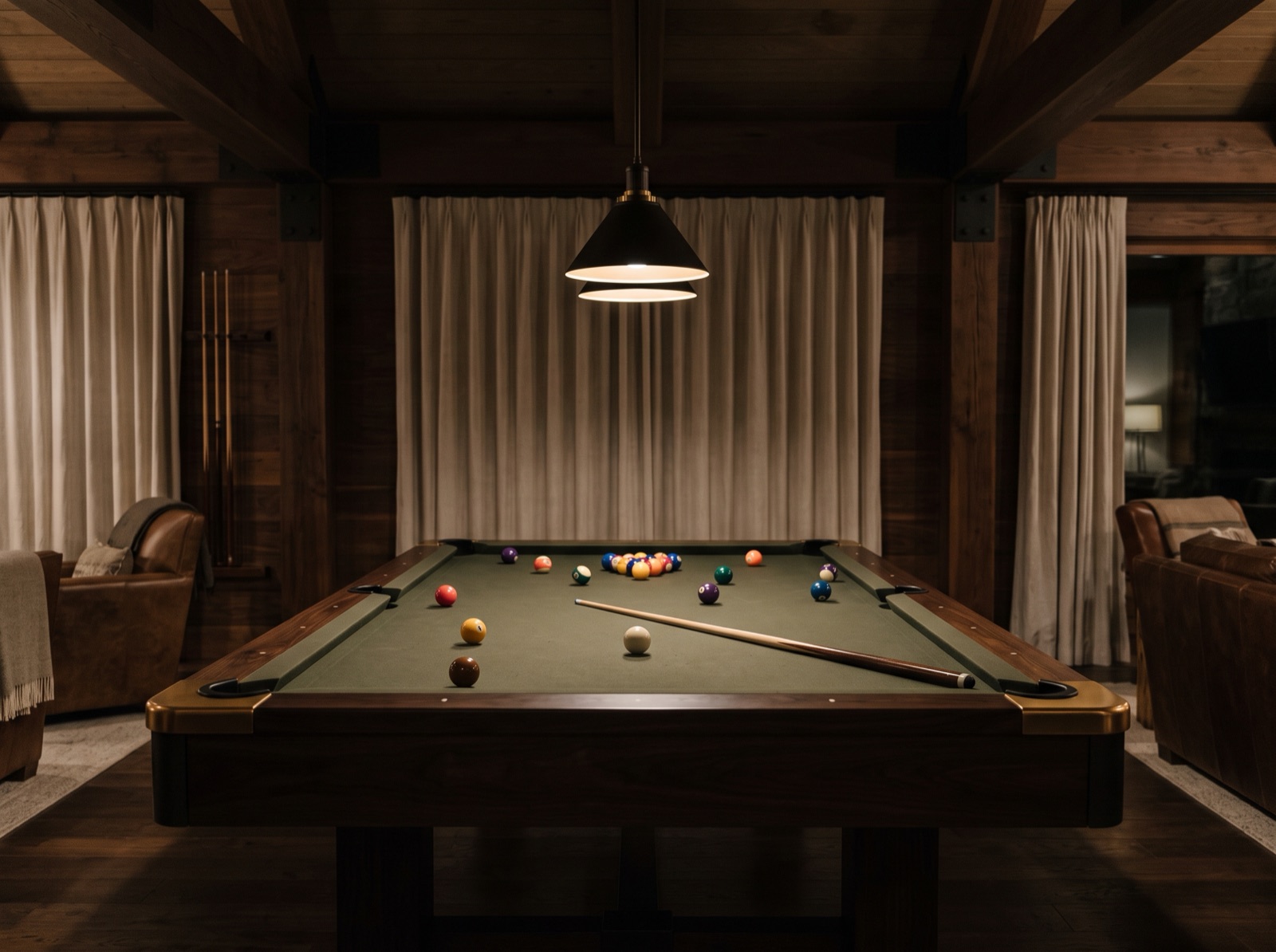 A pool table in the lodge rec room under warm lamp light