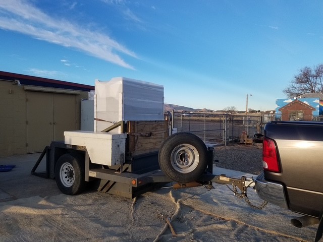 Wrapped safe on a drop-deck trailer hitched to a pickup.