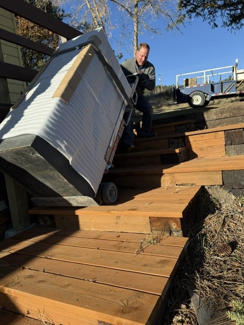 Motorized stair climber taking a padded safe up outdoor wooden stairs.