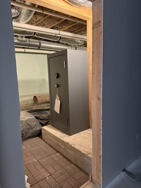 Gray safe being set through a floor opening into a basement.