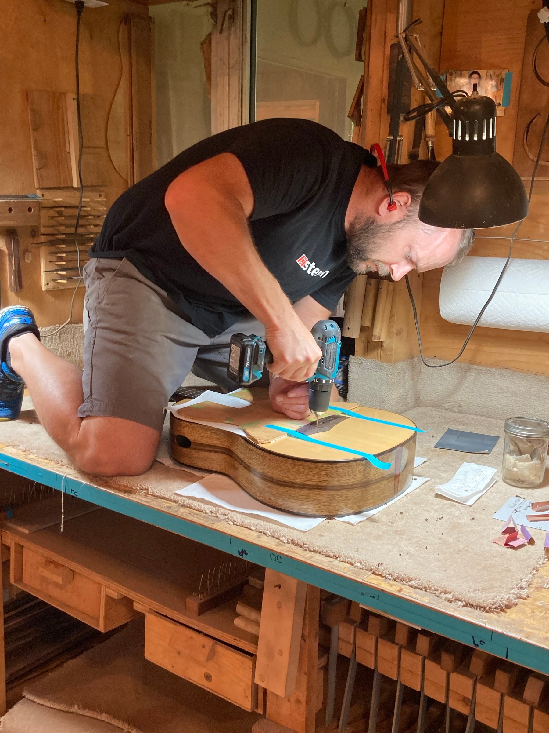 Jeremy Pappenfus over a guitar in progress at the workshop bench