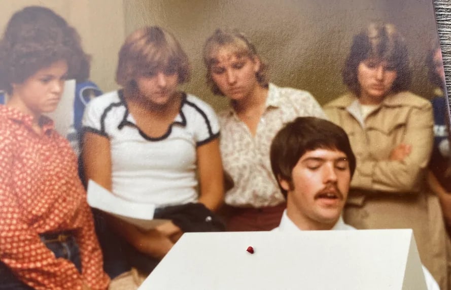 1970s photograph of people gathered around a large computer terminal